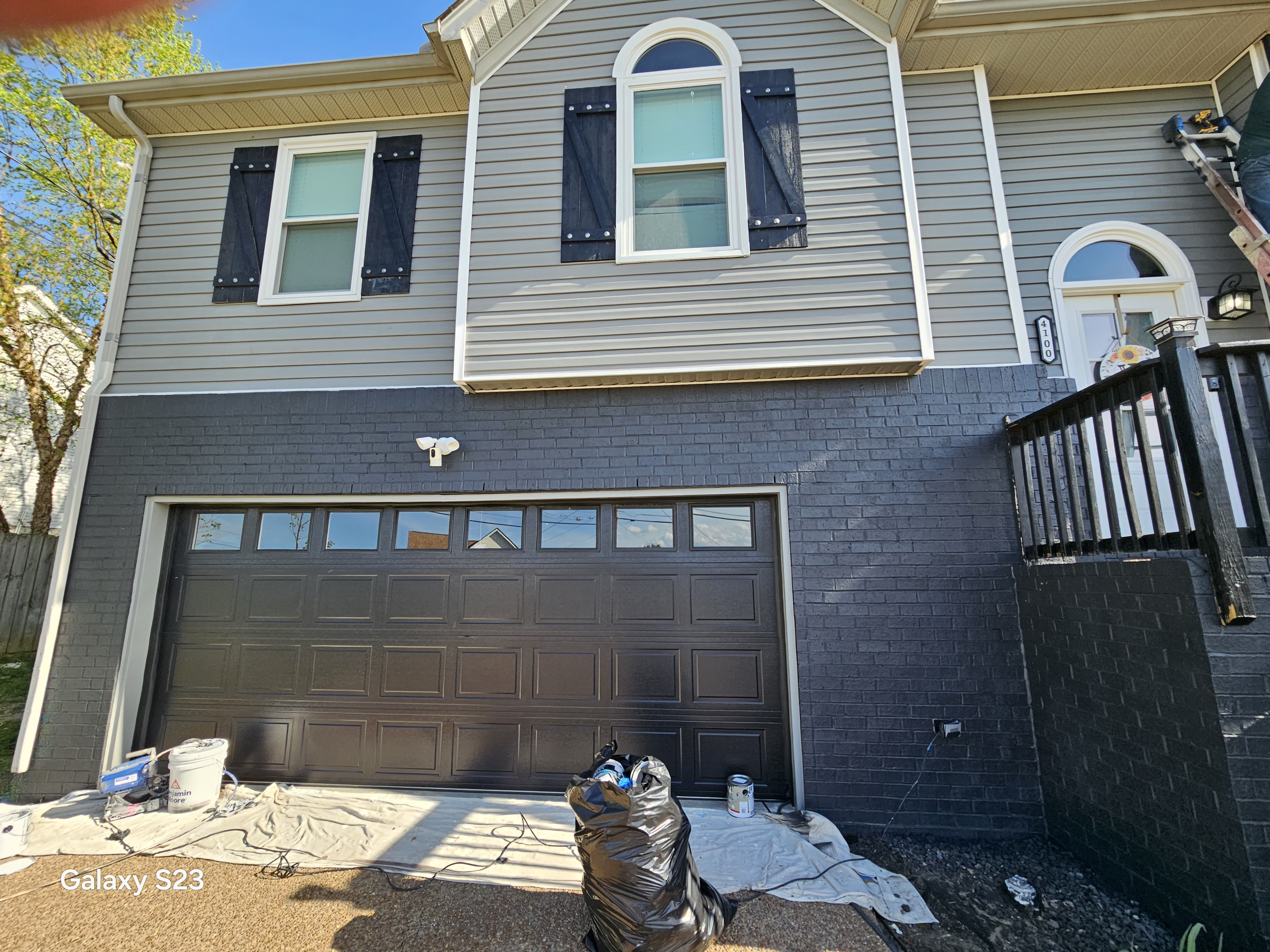 Dark brick garage foundation with fresh paint preparation underway
