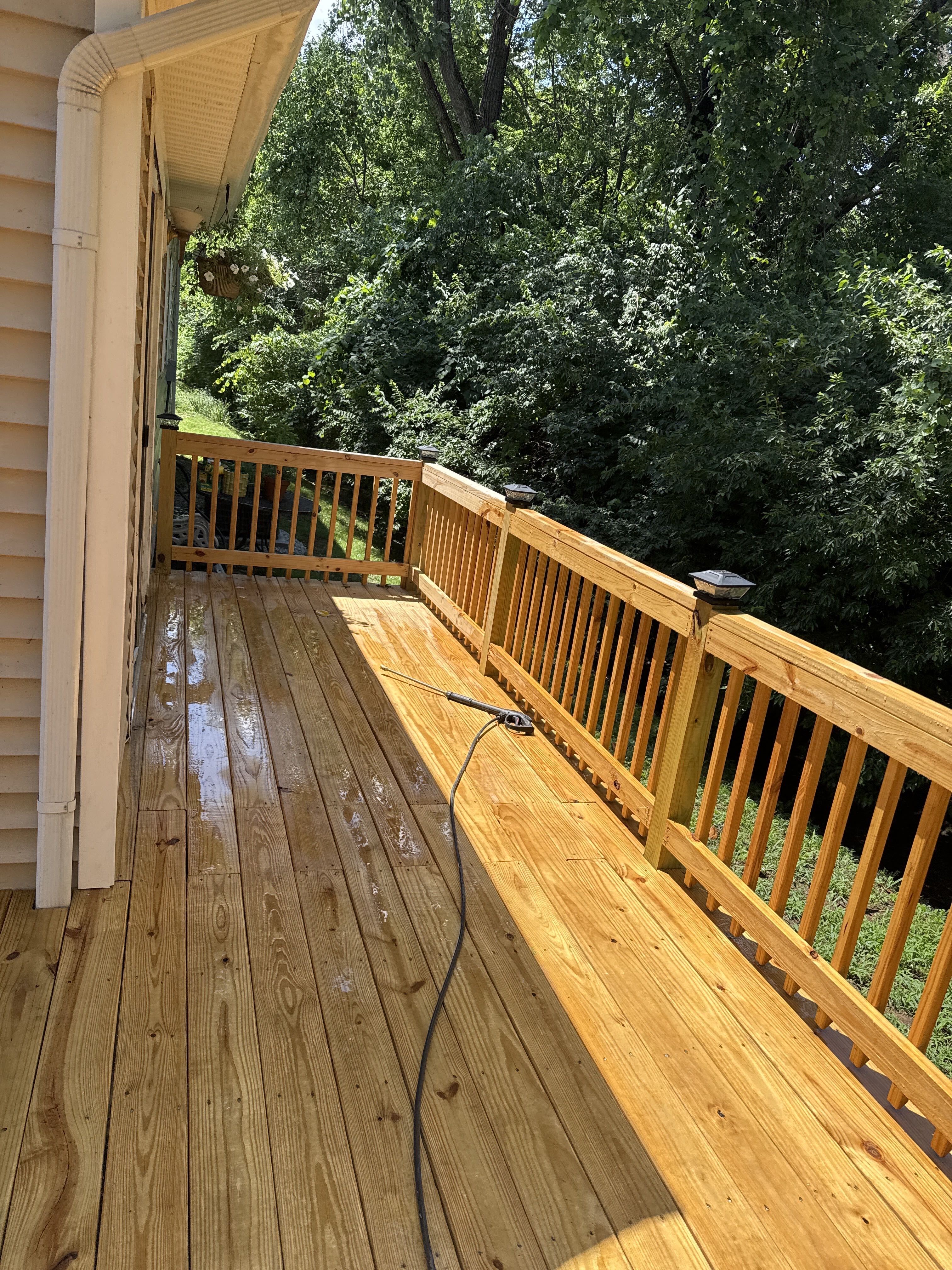 freshly stained wooden deck with railings overlooking tree line