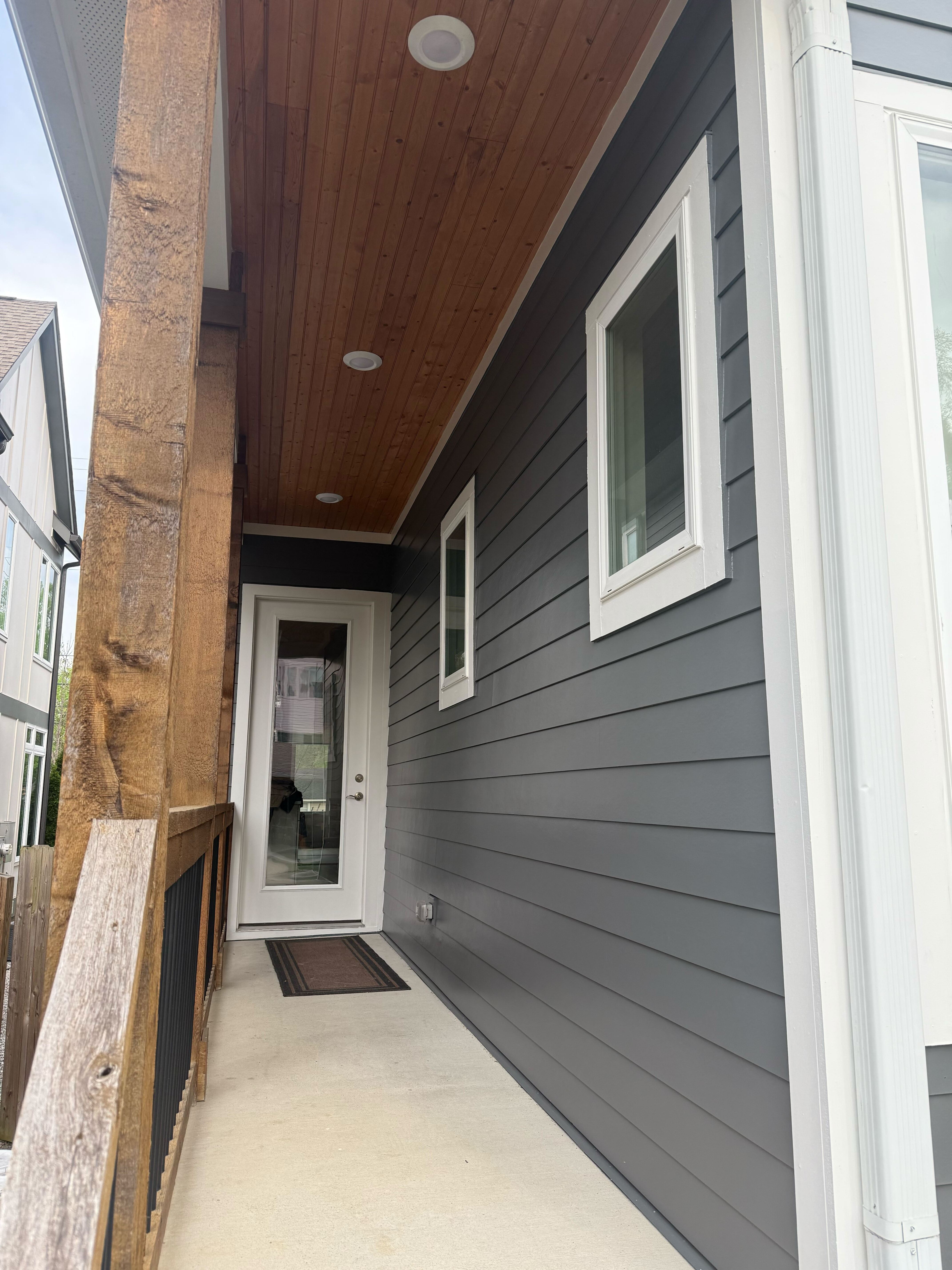 charcoal siding and dark wood ceiling on covered porch entry